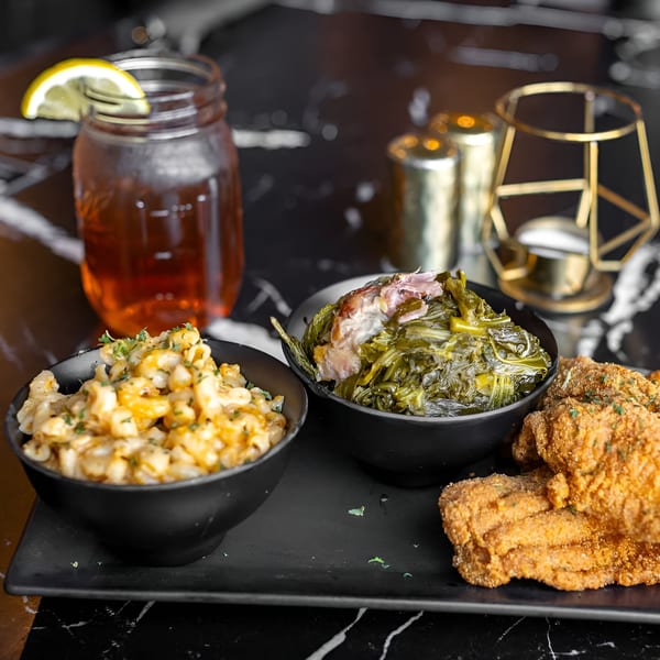 Soul food meal with fried fish, mac and cheese, collard greens, and iced tea.