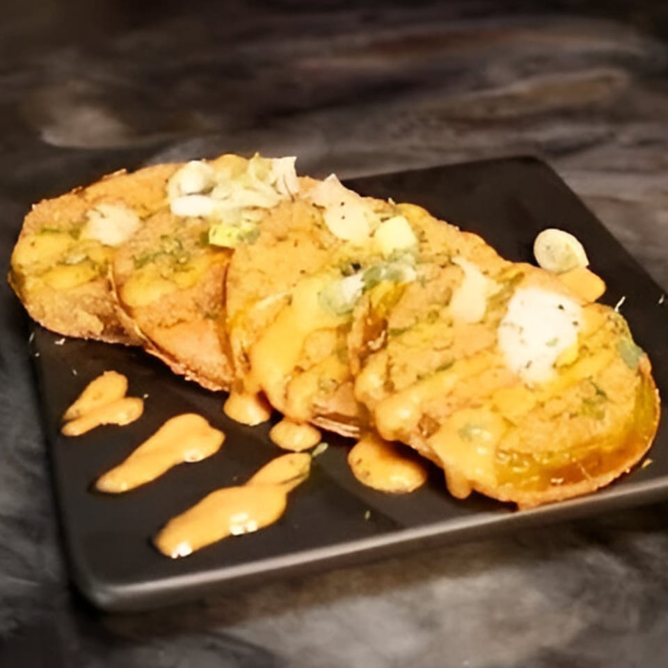 Three golden-brown fried green tomatoes topped with melted cheese, herbs, and a creamy sauce.