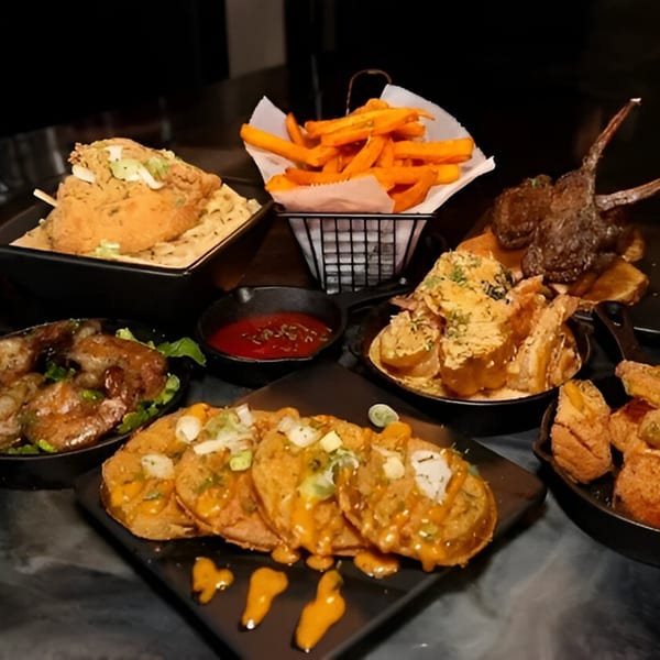 A table laden with various soul food dishes, including fried chicken, sweet potato fries, and loaded potato skins.