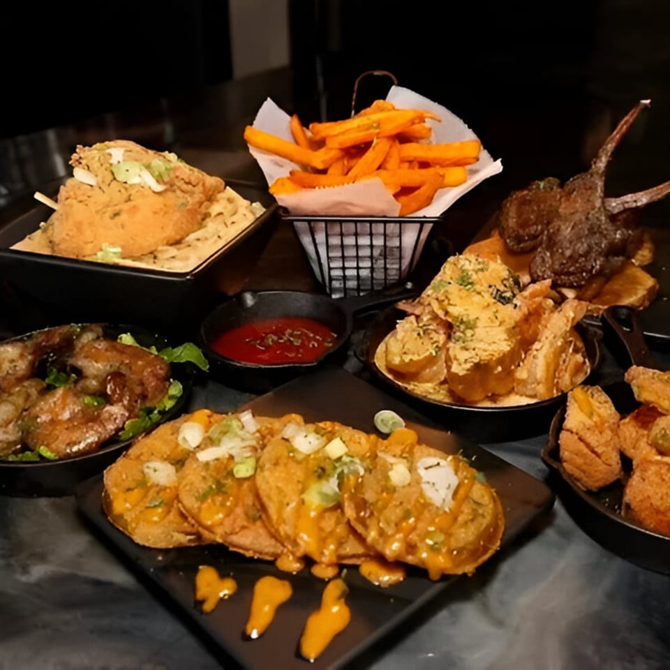 A table laden with various soul food dishes, including fried chicken, sweet potato fries, and loaded potato skins.