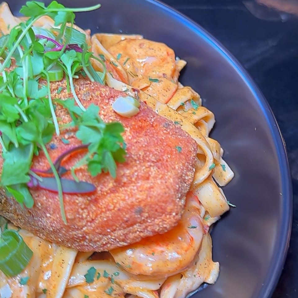Soule To Soule's salmon and shrimp pasta, topped with fresh greens and garlic.